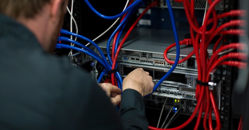 A person is plugging cables into a server