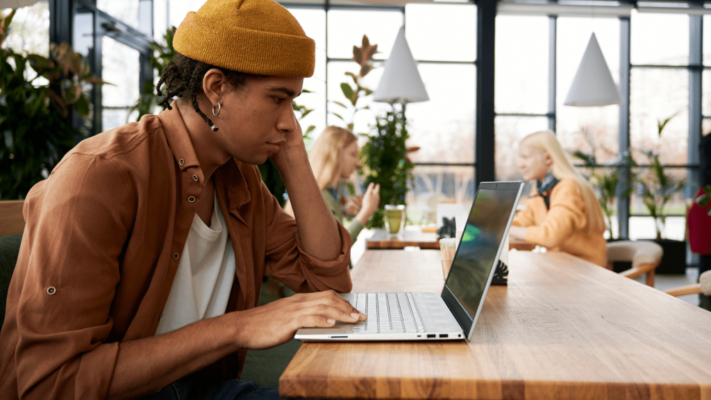 A person sitting at a wooden table while looking at a laptop