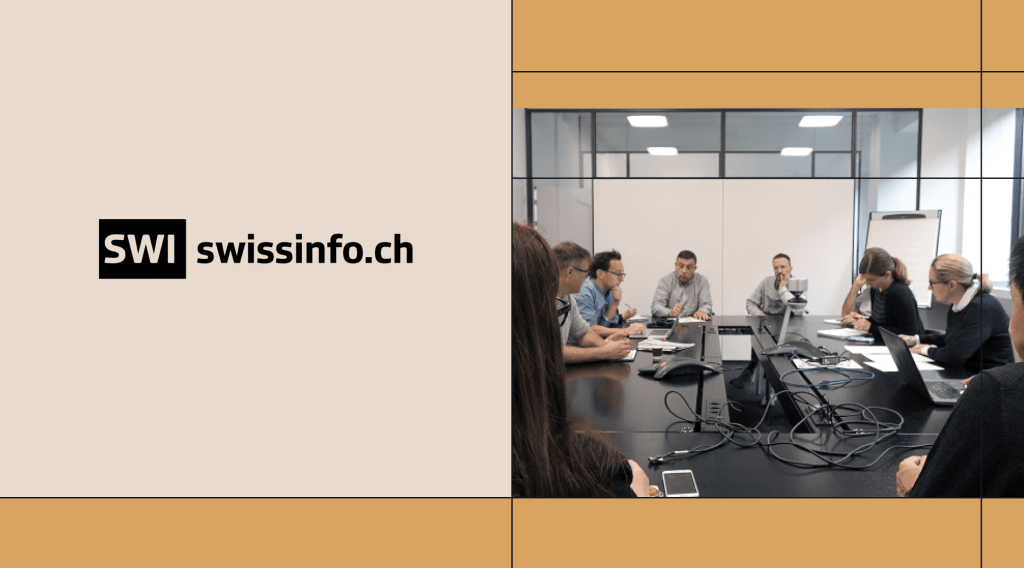 A group of professionals engaged in a discussion around a conference table in a modern office setting, with laptops, documents, and conference call equipment. The image features the SWI swissinfo.ch logo on the left side, framed by a structured design with beige and ochre-colored elements.