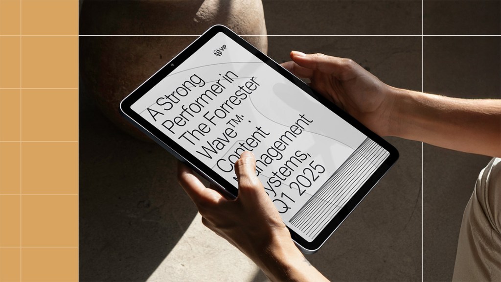 Person holding a tablet displaying the WordPress VIP announcement as a Strong Performer in The Forrester Wave™: Content Management Systems, Q1 2025 report.